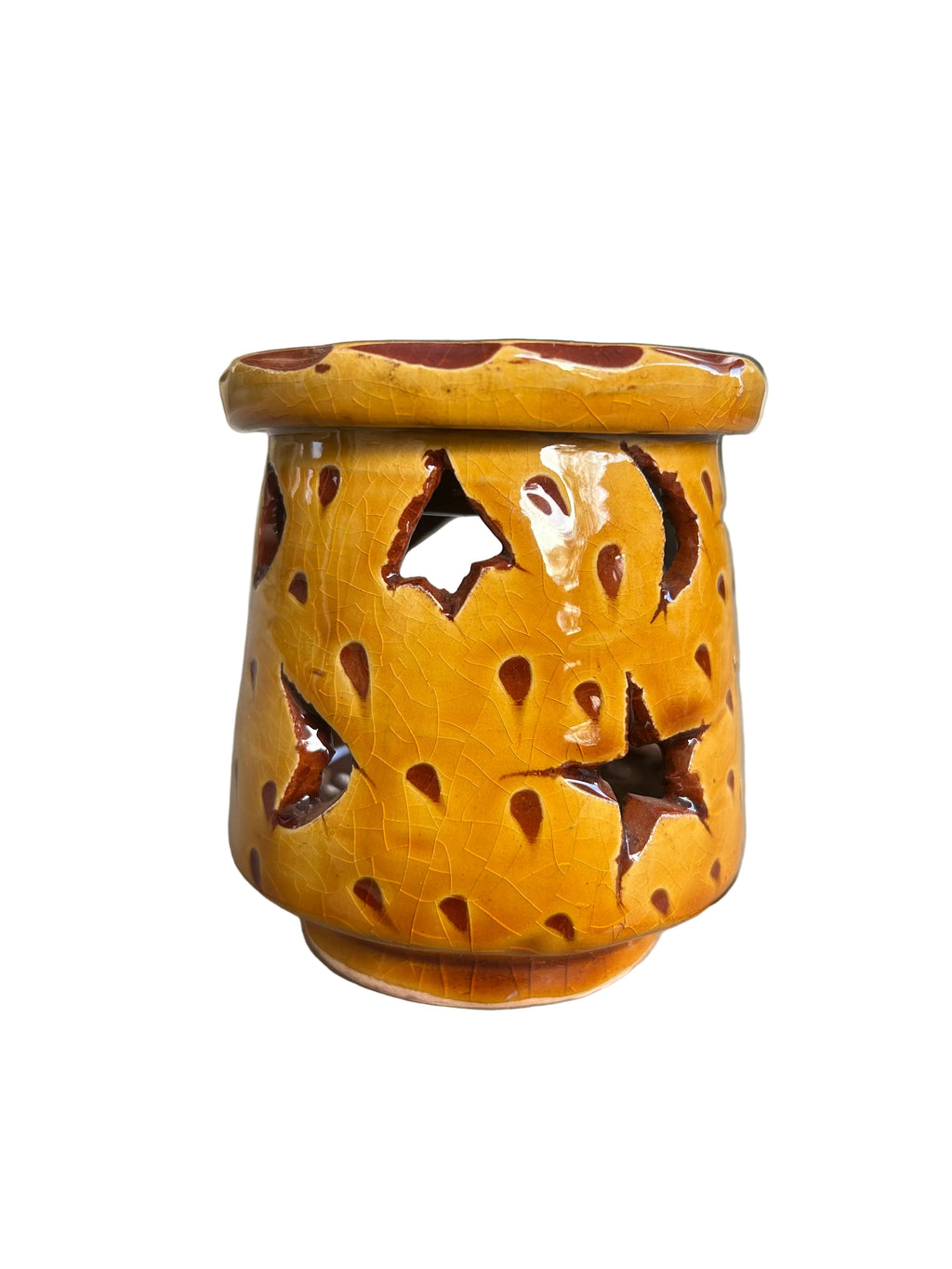 Brûle-parfum en céramique jaune, avec ouvertures ajourées, coupelle à bord ondulé et bougie chauffe-plat allumée à l’intérieur.