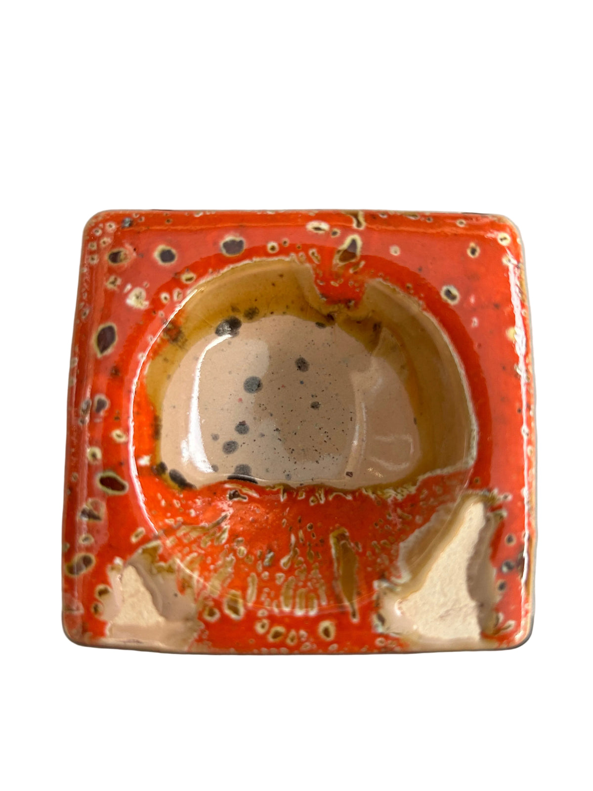 Brûle-parfum carré en céramique crème mouchetée et orange, avec motifs ajourés et bougie chauffe-plat à l’intérieur. 
