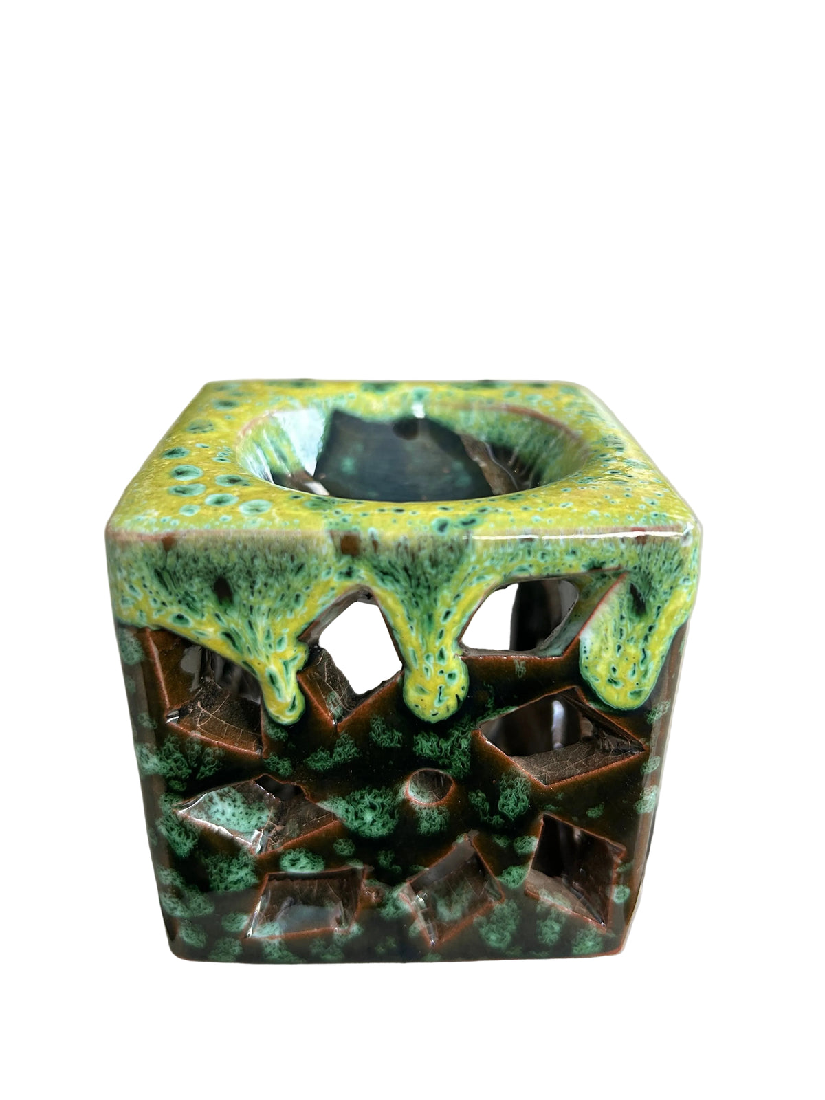 Brûle-parfum carré en céramique verte et marron, avec finition mouchetée, motifs ajourés et bougie chauffe-plat allumée.