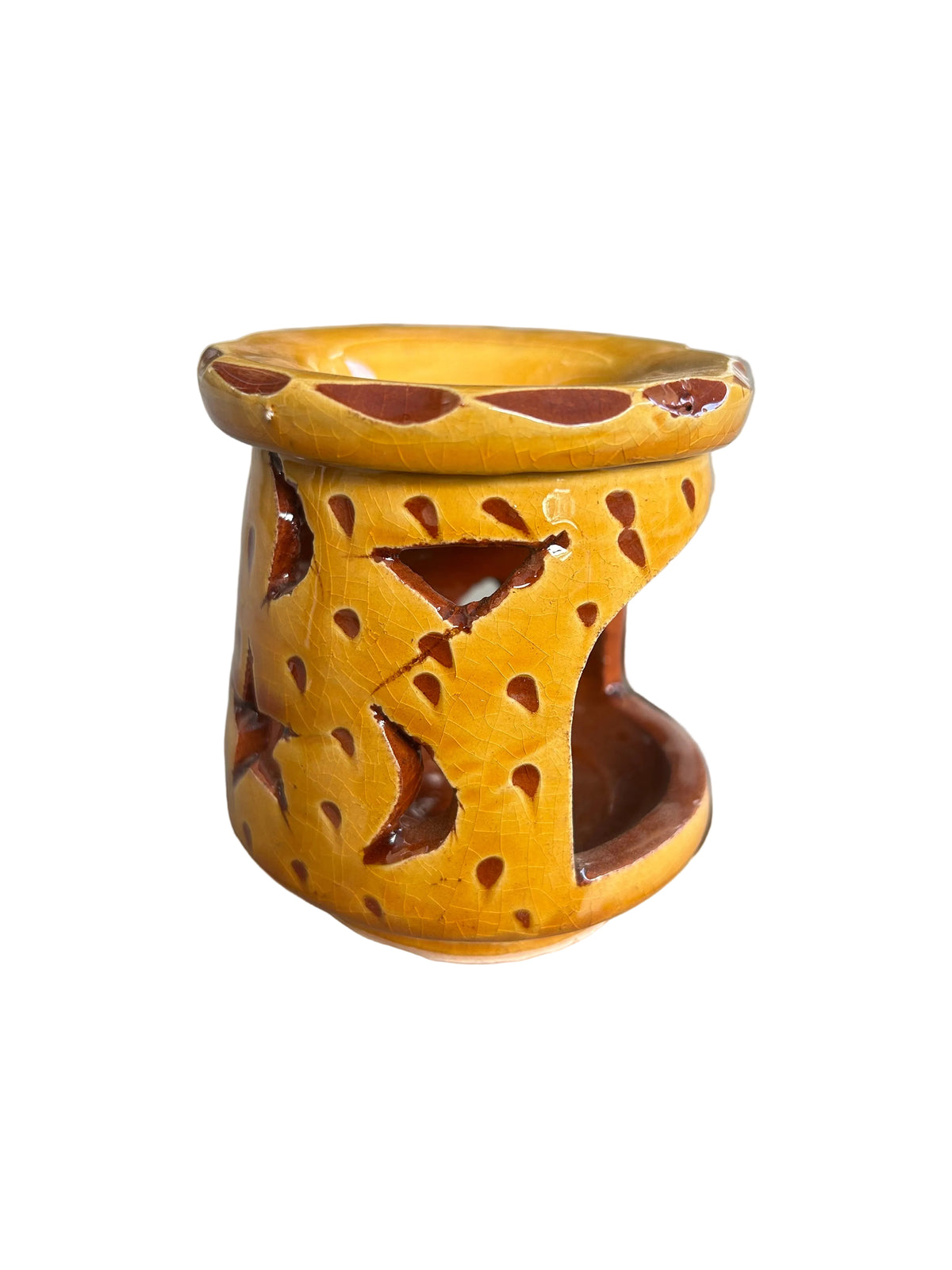 Brûle-parfum en céramique jaune, avec ouvertures ajourées, coupelle à bord ondulé et bougie chauffe-plat allumée à l’intérieur.