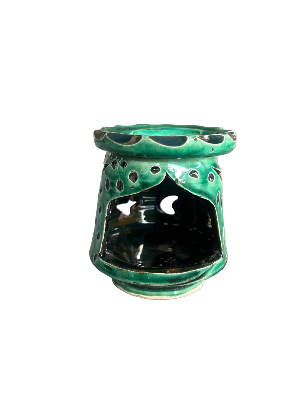 Brûle-parfum en céramique vert foncé brillant, avec lunes et étoiles ajourées, coupelle à bord ondulé et bougie chauffe-plat allumée.