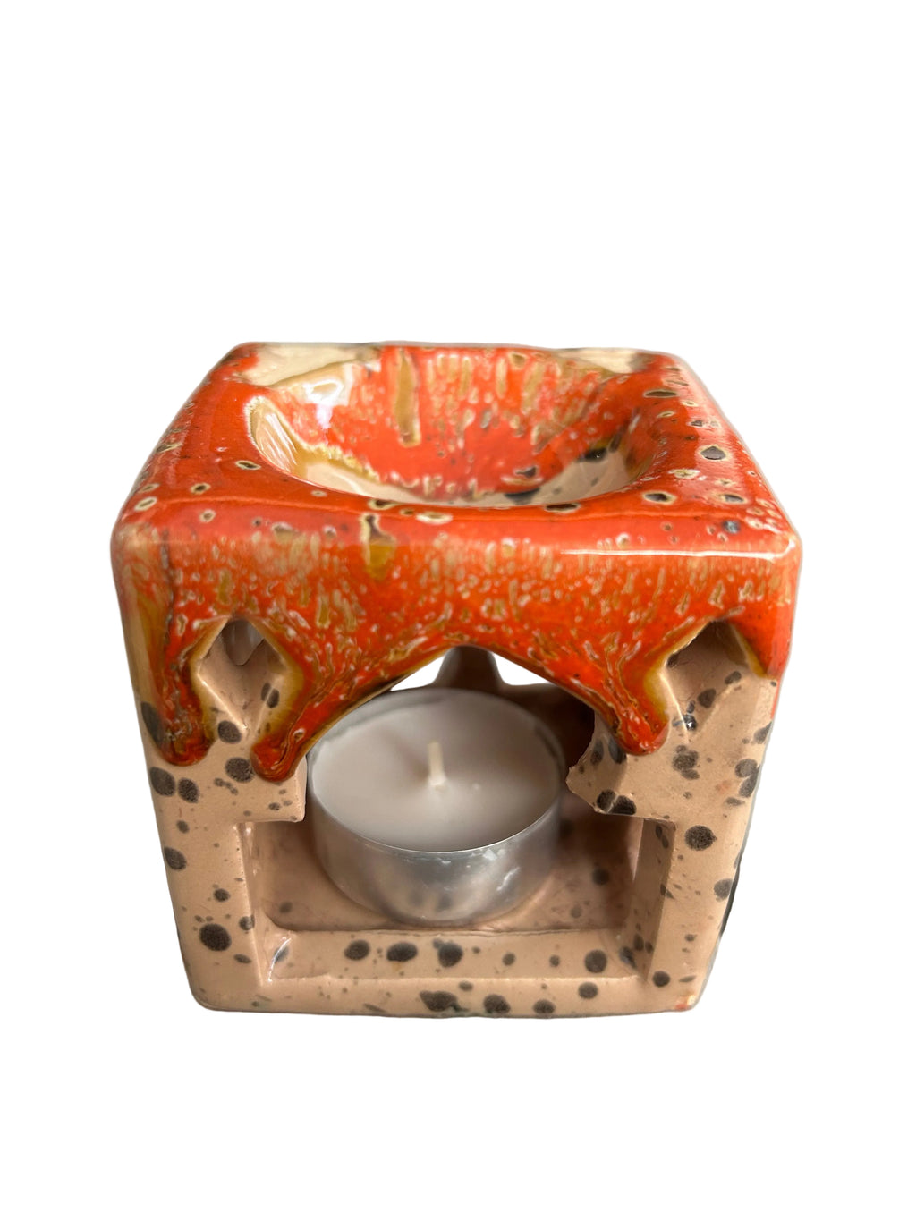 Brûle-parfum carré en céramique crème mouchetée et orange, avec motifs ajourés et bougie chauffe-plat à l’intérieur. 