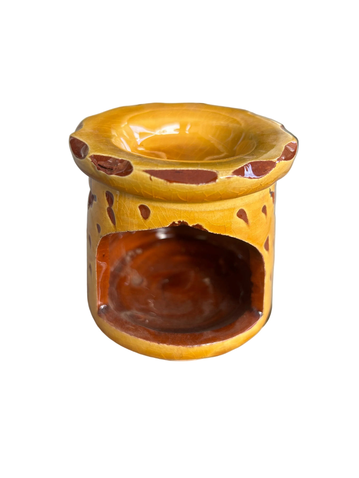 Brûle-parfum en céramique jaune, avec ouvertures ajourées, coupelle à bord ondulé et bougie chauffe-plat allumée à l’intérieur.