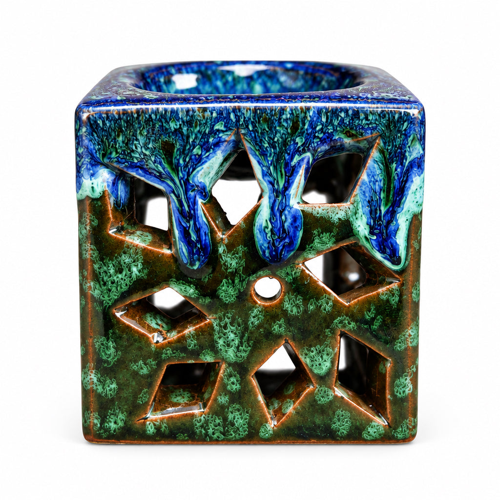 Brûle-parfum carré en céramique bleu marine, marron et vert, avec finition mouchetée, motifs ajourés et bougie chauffe-plat à l’intérieur.