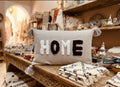 Housse de coussin HOME brodée à la main – gris et noir avec pompons berbères