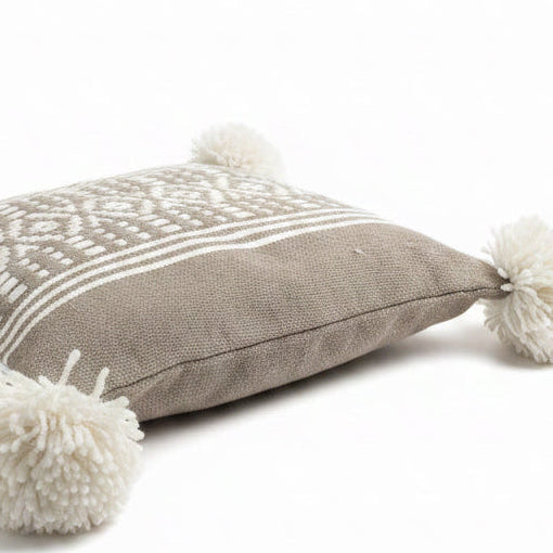 Housse de coussin artisanale taupe motifs berbères et pompons blancs – vue de côté fait main Maroc