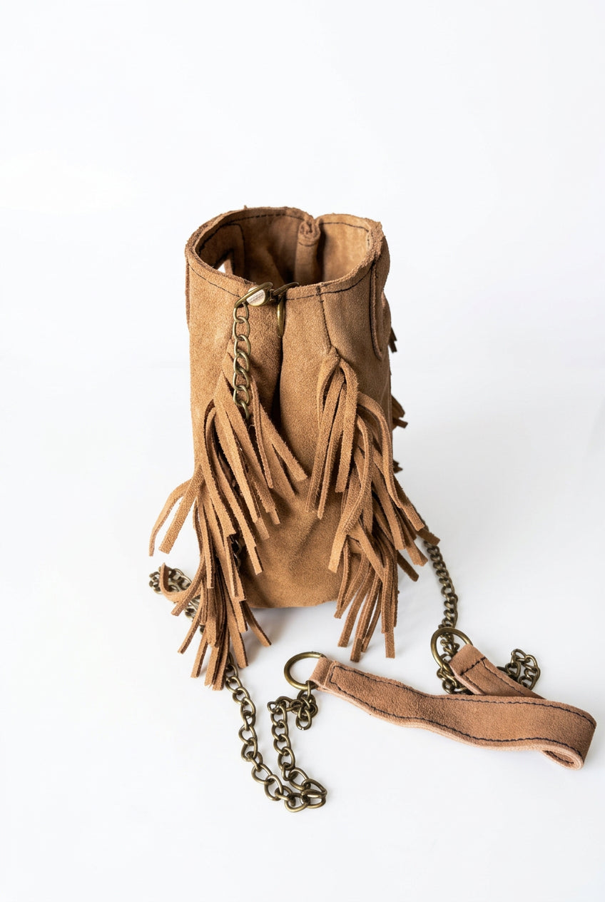 
« Sac Sienna en cuir camel à franges, avec bandoulière chaîne et poignées intégrées, style bohème. »