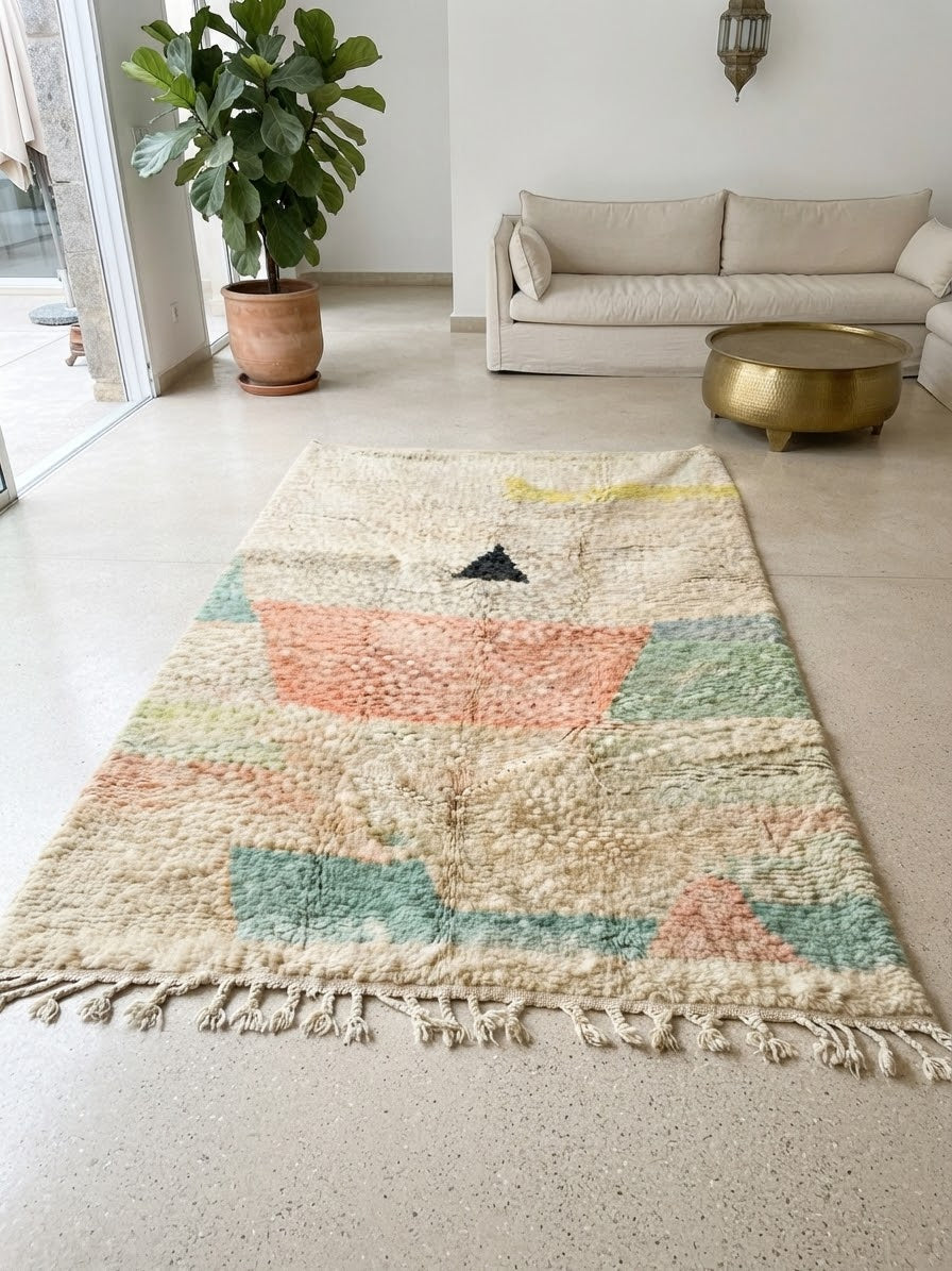 Tapis Beni Ourain suspendu dans un patio de riad – motifs géométriques pastels avec triangle sur fond ivoire