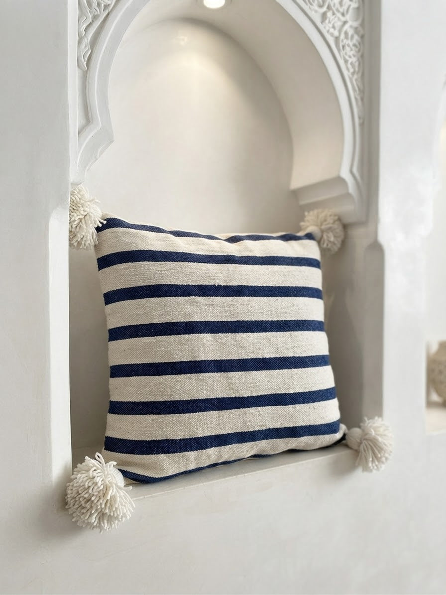 Vue de face housse coussin rayée bleu blanc – pompons naturels aux coins – fait main Maroc
