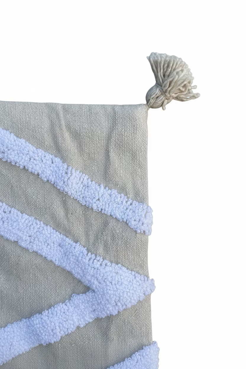 Détail gland et broderie tufted blanc sur housse de coussin lombaire beige sable – finition artisanale fait main au Maroc

