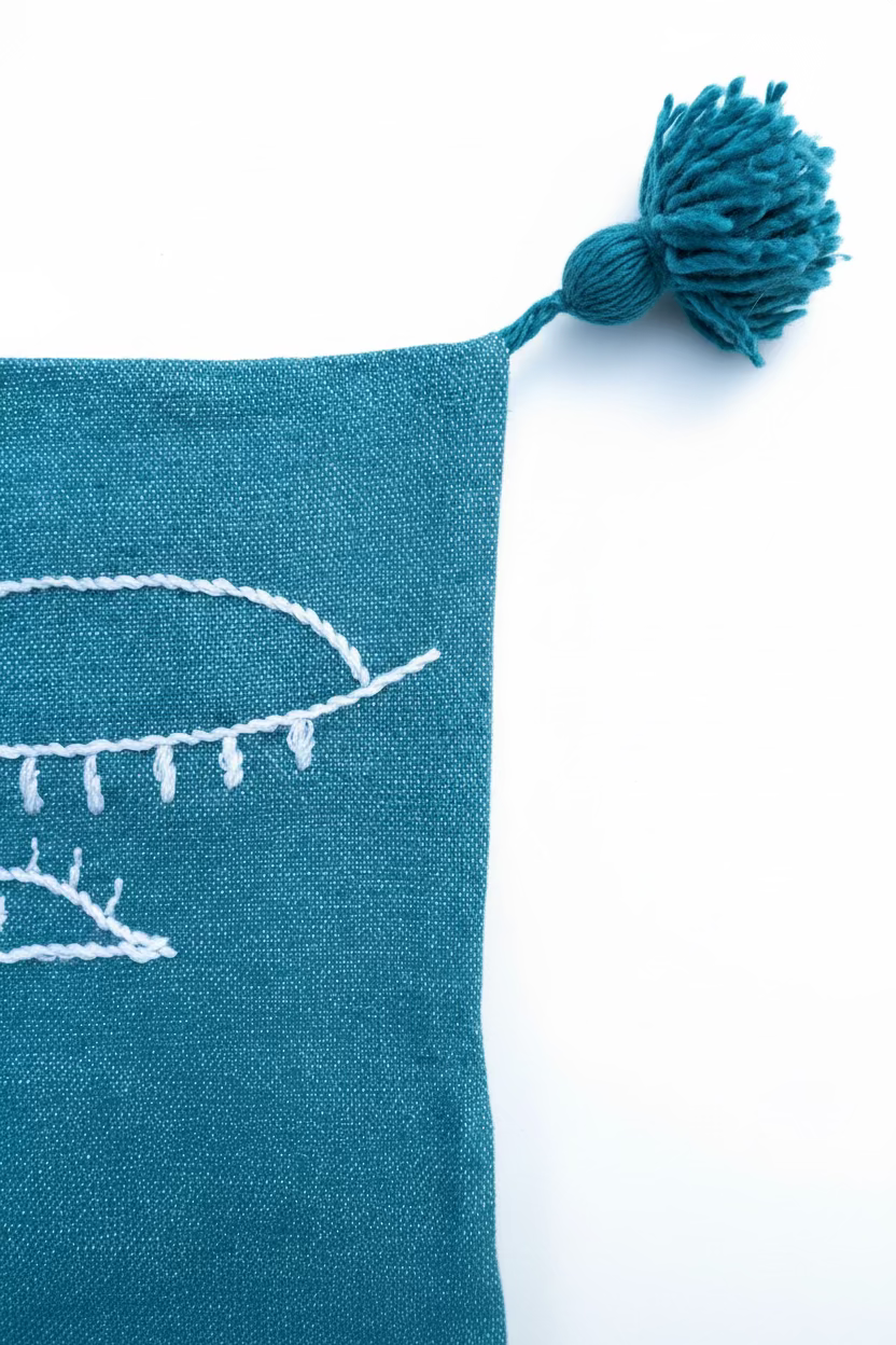 Pompons bleu pétrole aux coins – housse coussin brodée pièce unique – fait main au Maroc