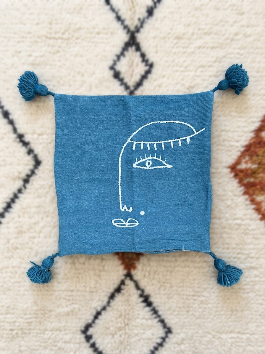 Vue de face housse coussin brodée bleu pétrole – motif visage – coton tissé main