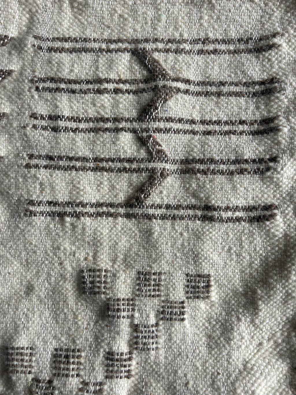 Gros plan tissage berbère artisanal – détail motifs flèches et carreaux brodés