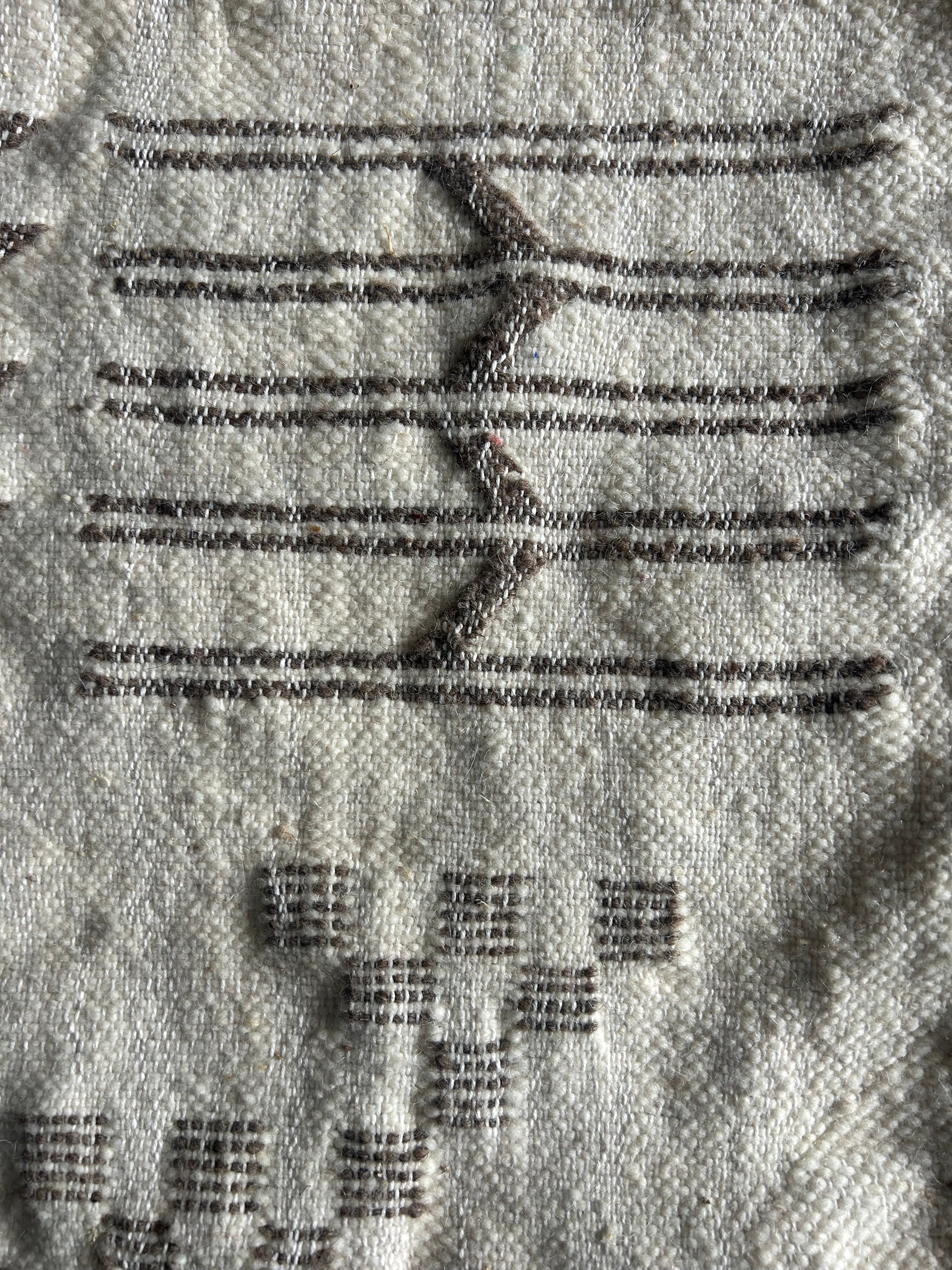 Gros plan tissage berbère artisanal – détail motifs flèches et carreaux brodés