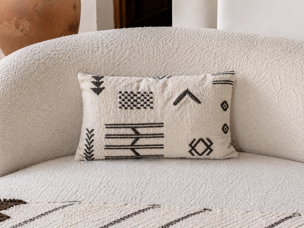 Coussin berbère ivoire et noir sur canapé boucle blanc – motifs graphiques flèches et losanges marocains