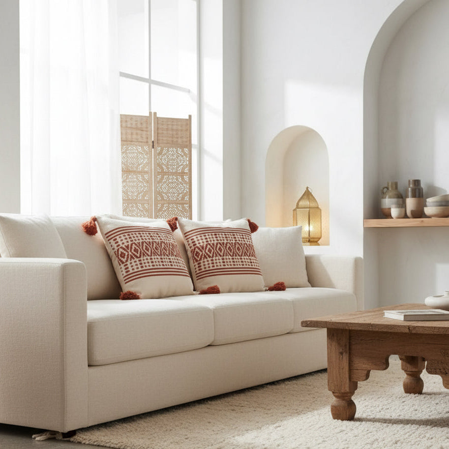 Duo de coussins boho marocains sur canapé blanc – motifs géométriques berbères et pompons terracotta