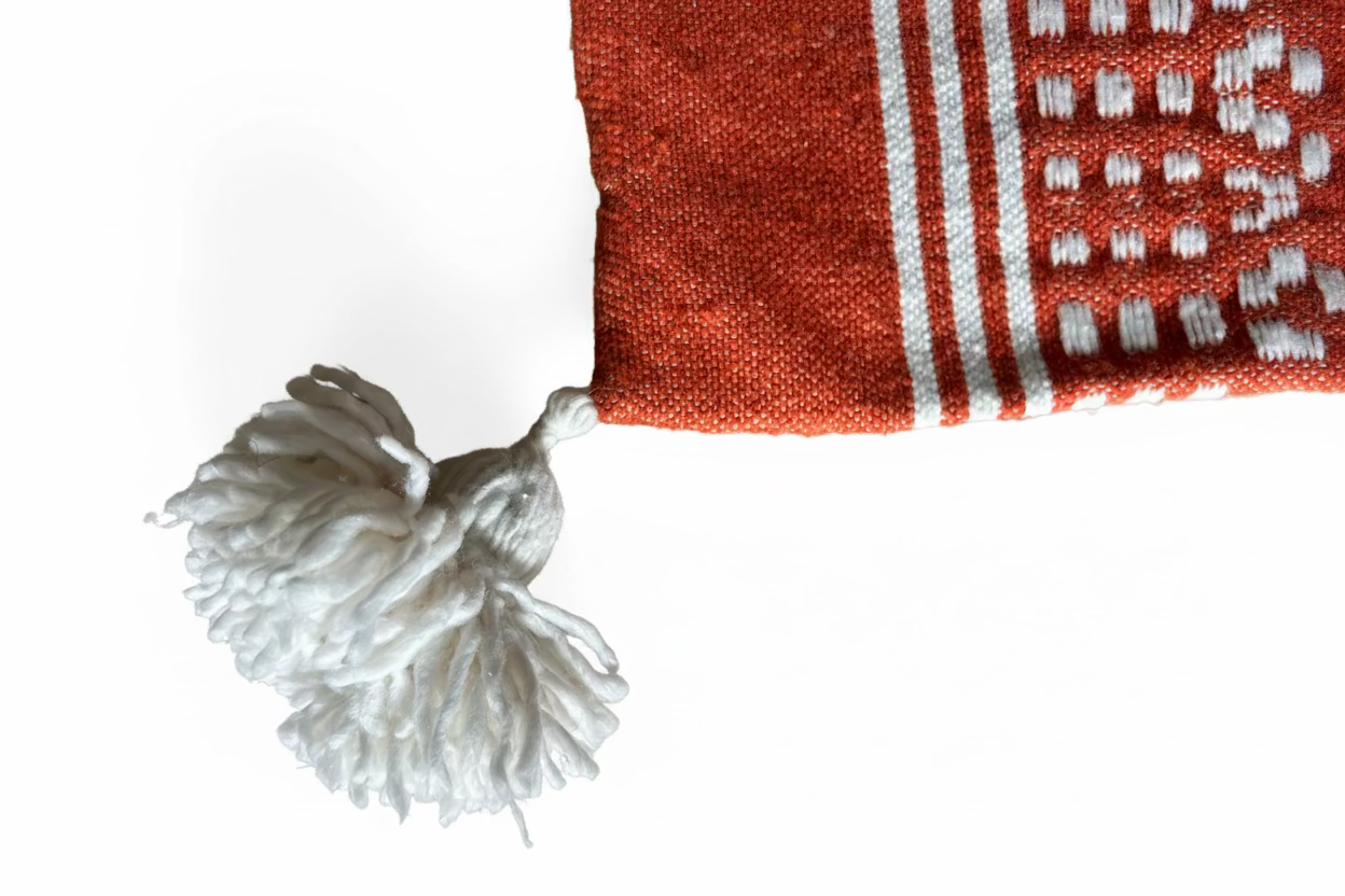 Détail pompon en laine écrue et tissage coton terracotta – Housse de coussin artisanale marocaine