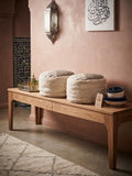 Deux poufs marocains en laine naturelle posés sur une table en bois, décor riad avec lanterne et zellige