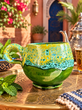 Tasse arrondie en céramique verte et jaune, avec anse incurvée, finition brillante et effets mouchetés turquoise sur la partie supérieure.