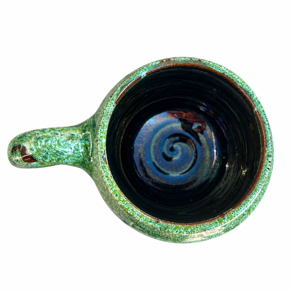 Tasse Émeraude à la forme arrondie, avec anse, finition brillante verte nuancée et base brun foncé.